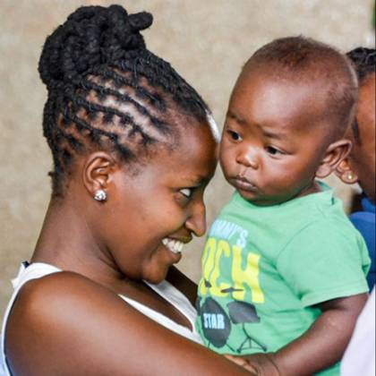 A young mother smiles and hugs her baby in Nairobi.