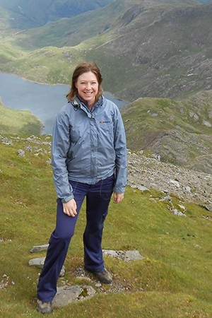 Katherine Robinson stands on top of a green mountain in Wales