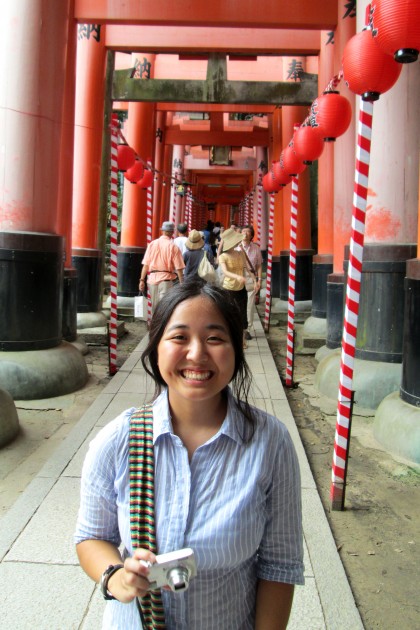 Girl holds digital camera and smiles in front of a city backdrop