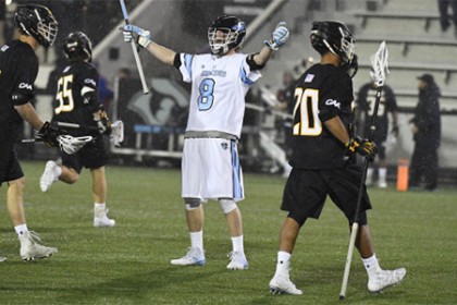 Hopkins player in white jersey raises both hands to celebrate goal