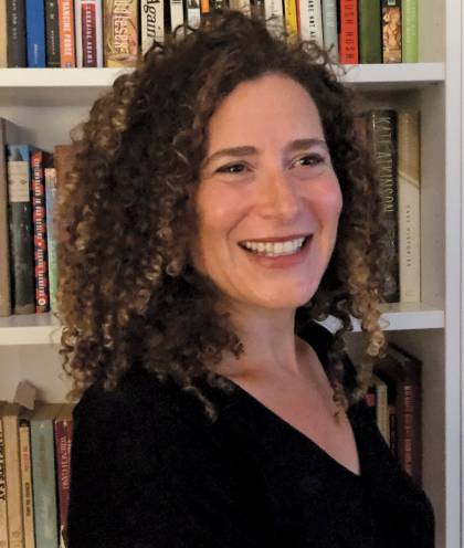 Photograph of Lizzie Skurnick standing in front of a bookshelf