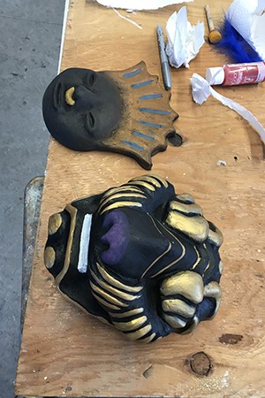 Two masks are displayed, one with a human face and one painted like a tiger
