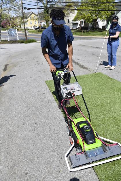 A student tests a modified lawnmower on astroturf