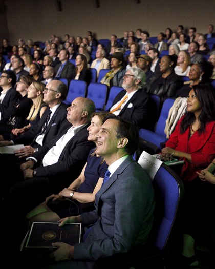Guests sit in rows of blue seats at theater opening