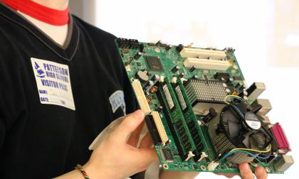 Johns Hopkins volunteer shows students a computer circuit board