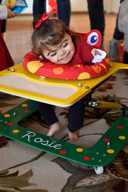 Rosie sits in her walker, smiling