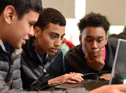 3 young men work together at a laptop computer 