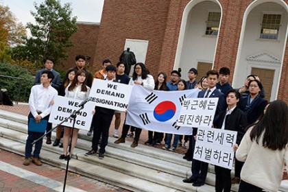 Students hold a South Korean flag and signs reading 