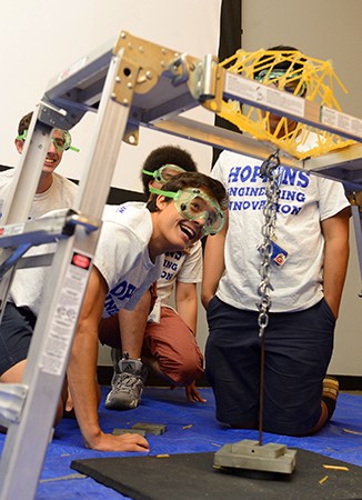 Team members watch from below as their spaghetti bridge breaks