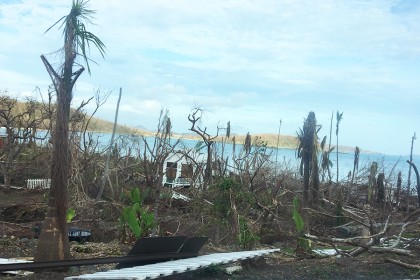A small white building stands amid downed and defoliated trees near the beach in St. John