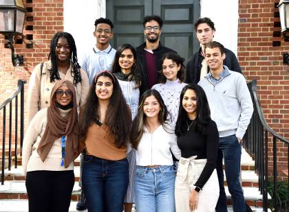 11 student volunteers pose for a photo on steps in front of brick home