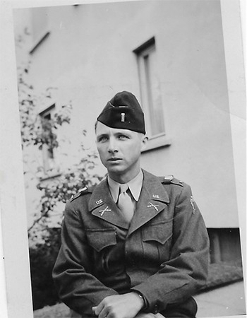 A black and white photograph shows a young man in a military uniform and beret