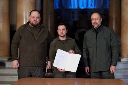 Three men hold an official document