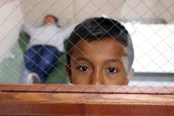 A child looks out the door window from the room he is staying in at the Brownsville, Texas port of entry