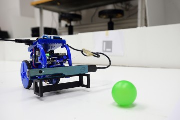 A robot pauses in front of a bright green plastic ball