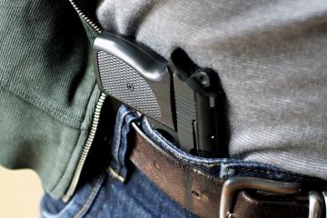 A handgun is tucked inside a person's belt