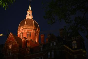 A photo of the dome of the old Johns Hopkins Hospital, lit up with orange light in the dark