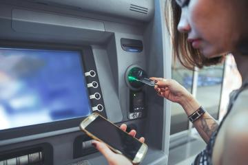 A woman inserts her bank card into an ATM