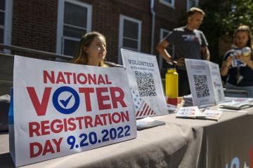 Volunteers stand behind a sign advertising National Voter Registration Day