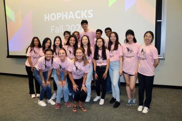 A group of people in pink HopHacks tee shirts