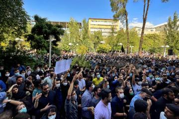 A large crowd of students from Amirkabir University protest outdoors with the backdrop of trees and blue sky against hijab and the Islamic Republic