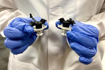 A gloved researcher hold two PeriPath devices that resemble spools of wire