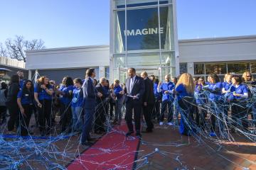 People celebrate a ribbon cutting with streamers