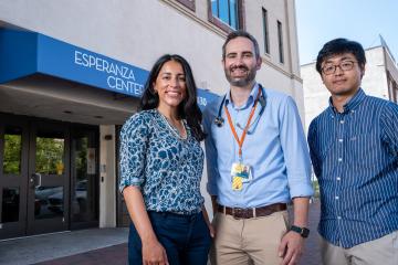 Three people stand in front of the Esperanza Center entrance