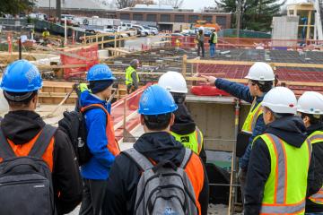 A group of people in hard hats look over a building site
