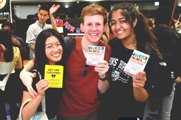 Photograph of a trio of smiling Johns Hopkins students holding club fliers