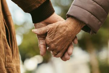 Elderly people hold hands