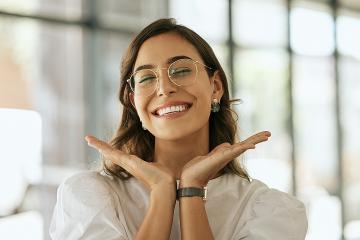 Cheerful businesswoman with glasses posing with her hands under her face showing her smile 
