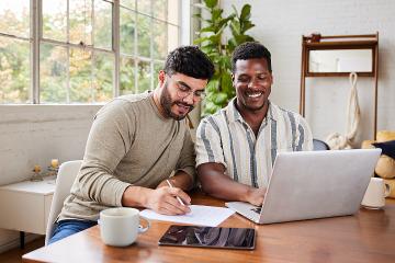 Smiling young male couple going over their home finances together