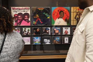 People stand in front of a display of record sleeves and CD covers at the BMA's exhibit 