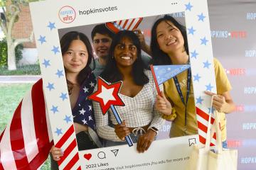 Four students pose in a frame meant to look like a Hopkins Votes Instagram post.
