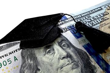 A graduation cap sits atop Ben Franklin's head on a $100 bill.