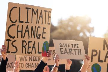 Protestors hold up cardboard signs with slogans about the reality of climate change
