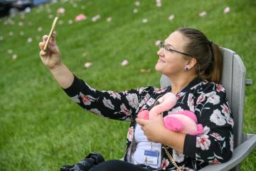 A person takes a selfie while holding a flamingo stuffed animals