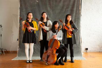 The four members of Bergamot String Quartet pose holding their instruments