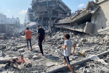 Two adults and a child walk through the rubble of destroyed buildings in Gaza City
