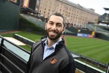 Johns Hopkins University alum Mike Snyder at Oriole Park at Camden Yards, with the playing field and B&O Warehouse visible in the background