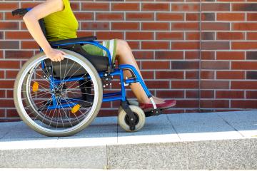 Adult woman steering her wheelchair up a ramp