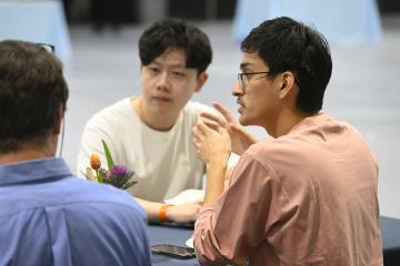 Three students talk around a table.