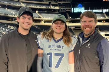 Carter Hogg (center) pictured in a football stadium with brother FJ (left) and dad Jason