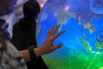 Close-up of a hand touching a blue and green globe