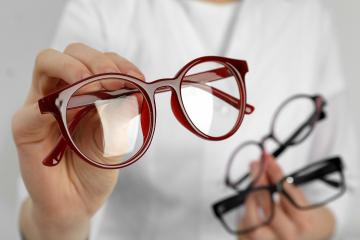 An optometrist shows three pairs of glasses to a customer.