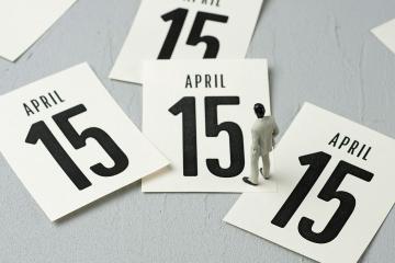 Businessman figurine stands on calendar pages that say April 15