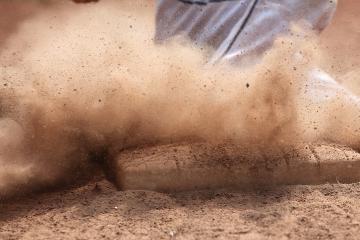 Dirt flies as a player’s foot slides into a base