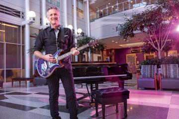 Oncologist Bill Nelson stands in the lobby of the Sidney Kimmel Cancer Center holding a guitar