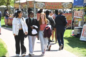 three students walk past a stand selling funnel cakes